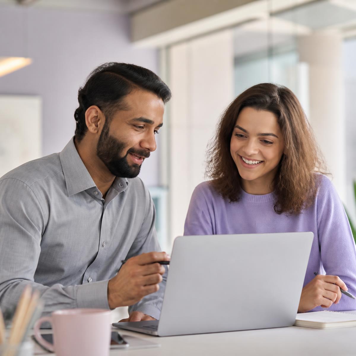 Two colleagues working through an online AI training module on a laptop